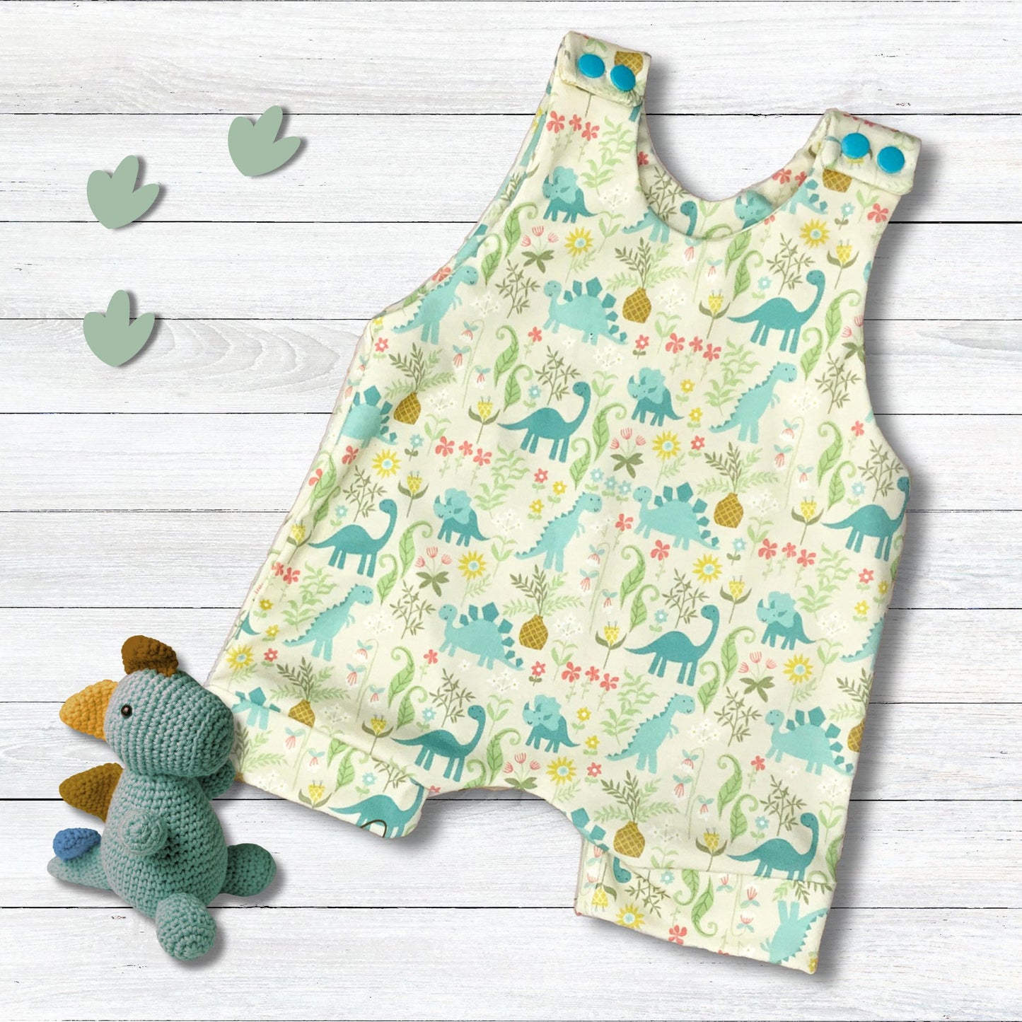 Cute dinosaur print in shades of teal on a light cream background with matching snaps