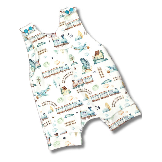 Cute trains and planes print in shades of blue and tan on a white background.  Short summer romper for boys with matching blue snaps.